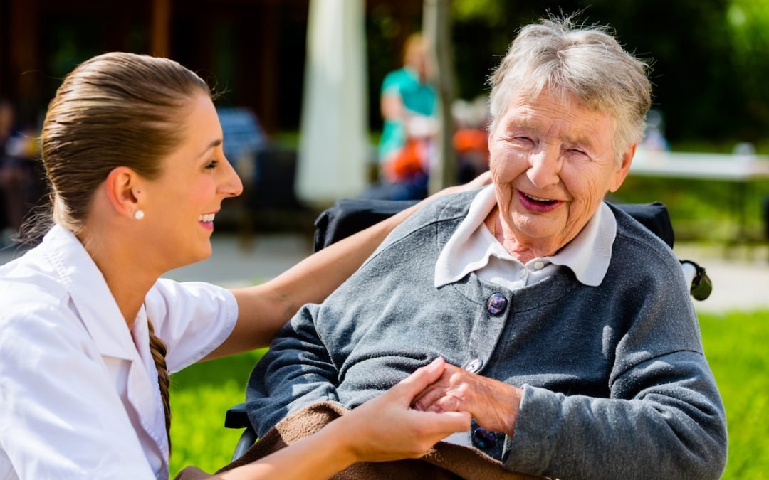 Nurse holding hands with senior woman in wheelchair